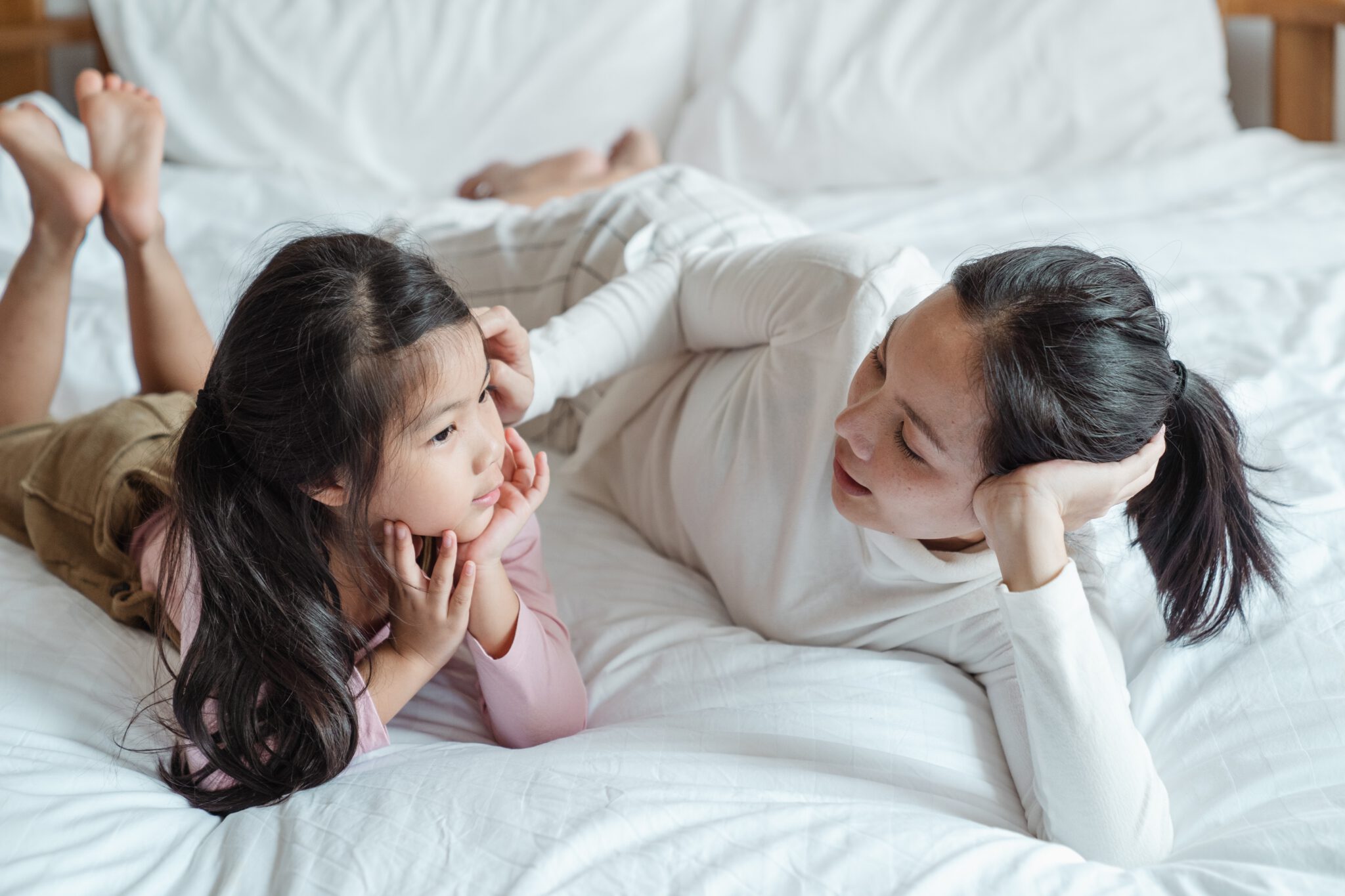 Moeder die met haar kind op bed ligt en praat over heftige nieuwsberichten