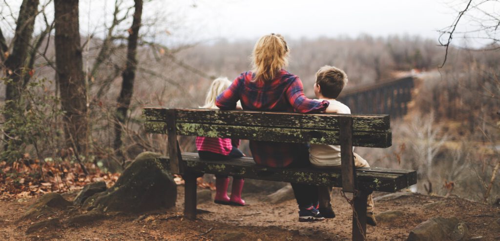 moeder en kinderen zitten op een bankje in de rustige natuur