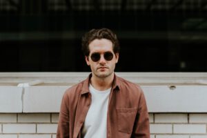 mentale gezondheid / man met zonnebril leunt tegen muur