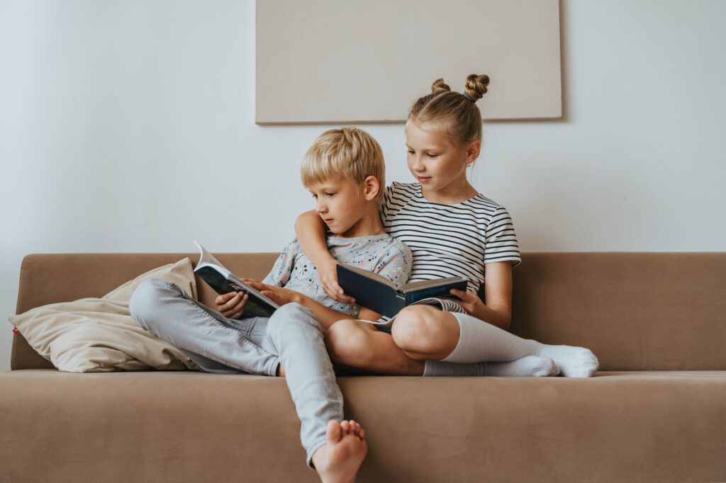 band tussen kinderen / broer en zus zitten te lezen op de bank