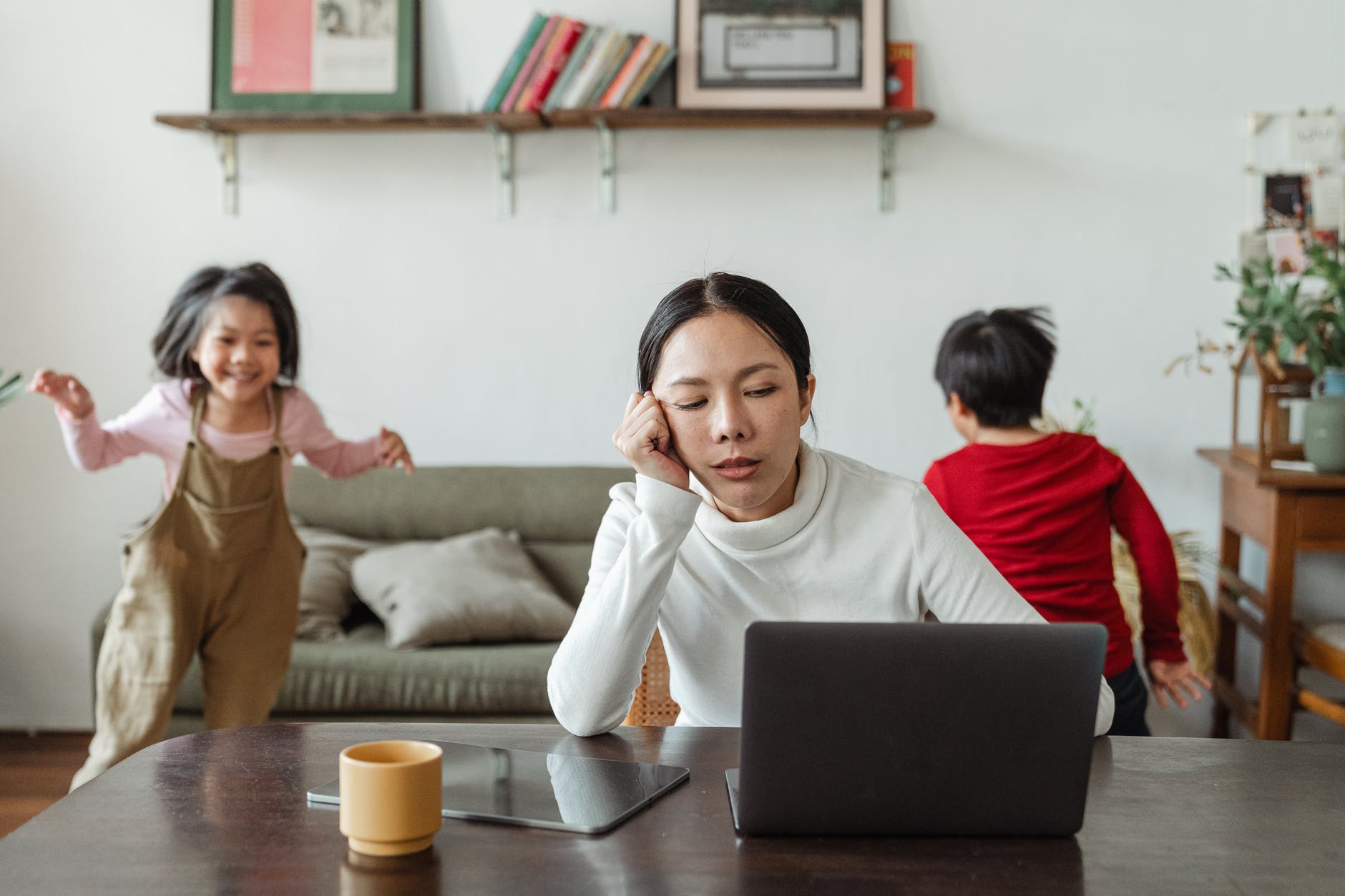 geduld / moeder aan tafel met laptop met kinderen op achtergrond