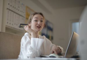 Kind gaat beleggen. Meisje achter de computer met creditcard