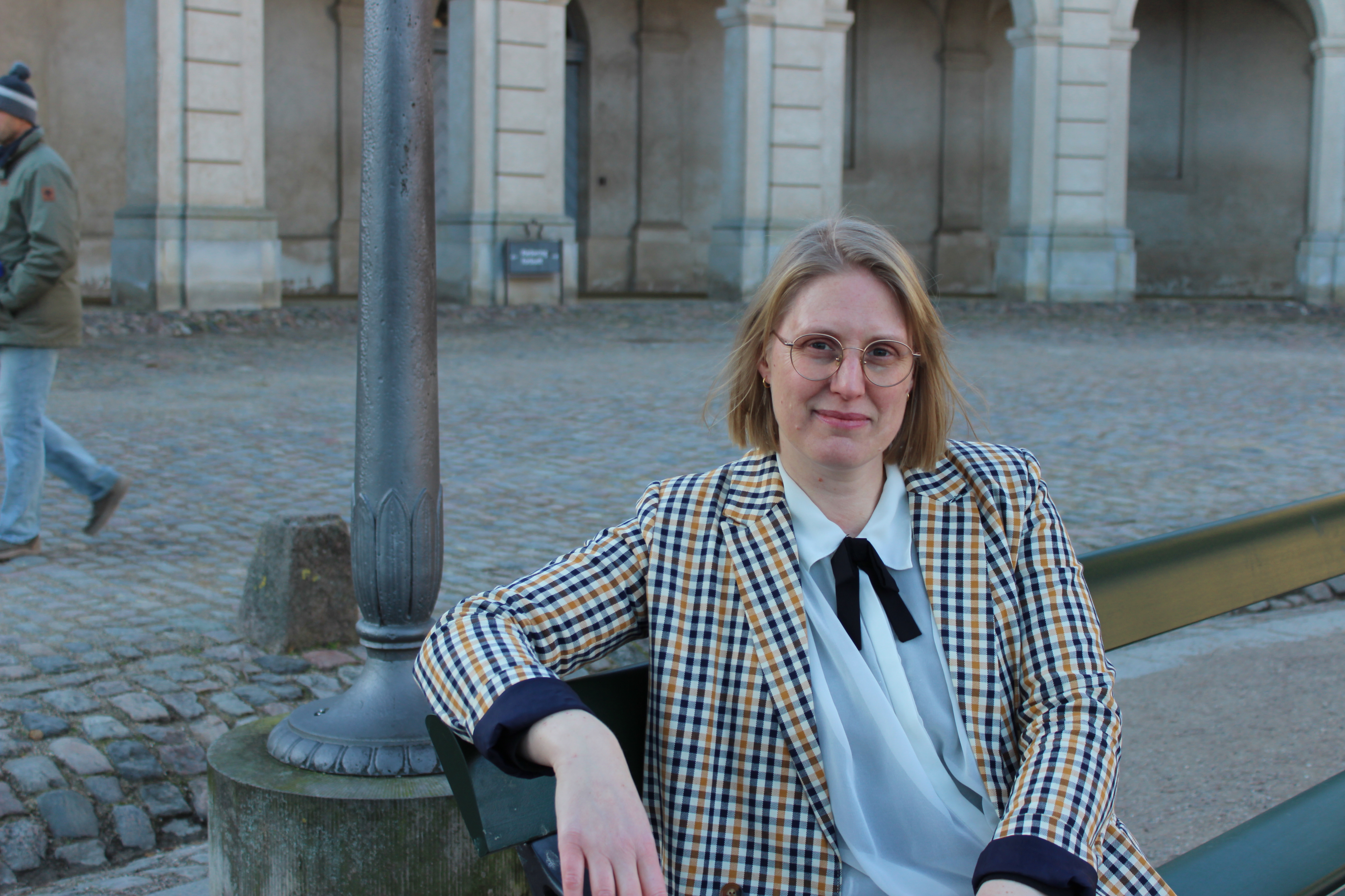 Vrouw met geruite blazer en witte blouse met strik